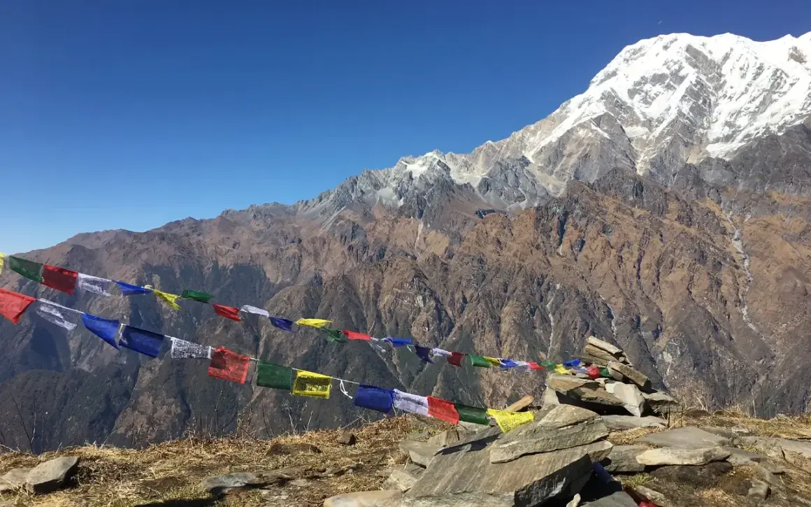 Vackra böneflaggor fladdrar i vinden under en snöklädd bergstopp. En oförglömlig upplevelse av att vandra i Nepal.
