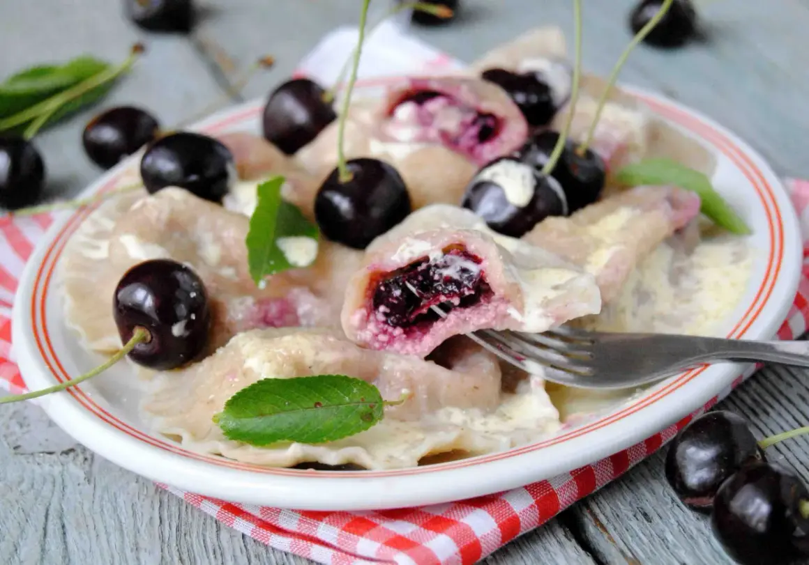 Pyszne pierogi z czereśniami, polane śmietaną, ozdobione świeżymi owocami i listkami mięty. Idealne na letni deser.