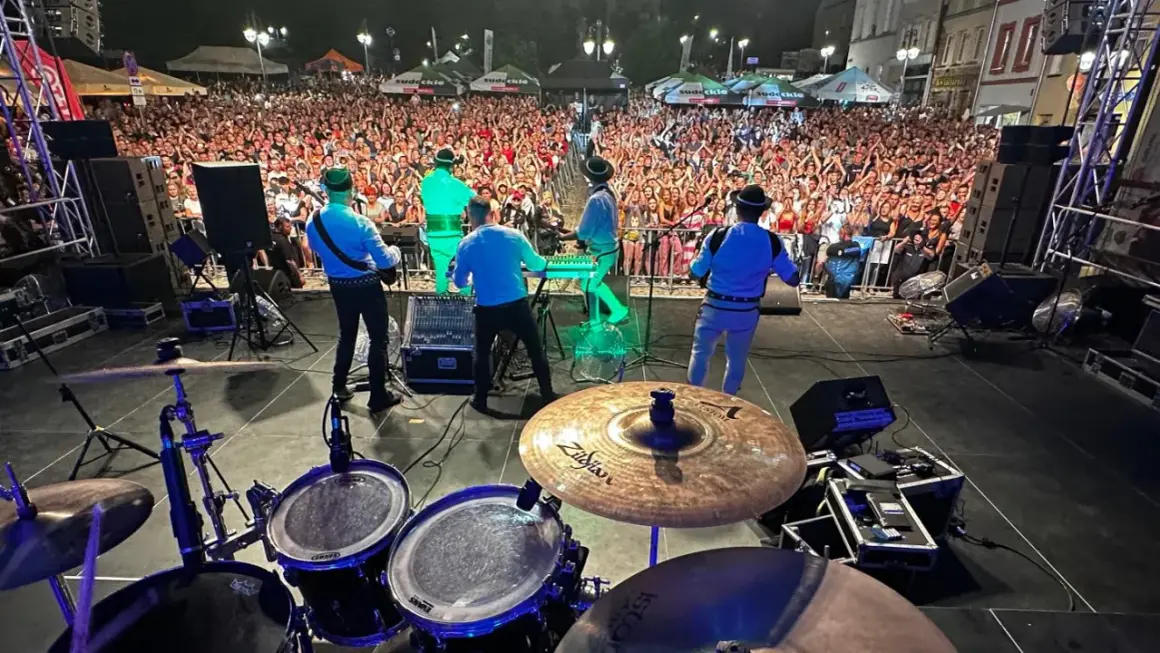 Baciary członkowie zespołu grają na scenie dla tłumu fanów.