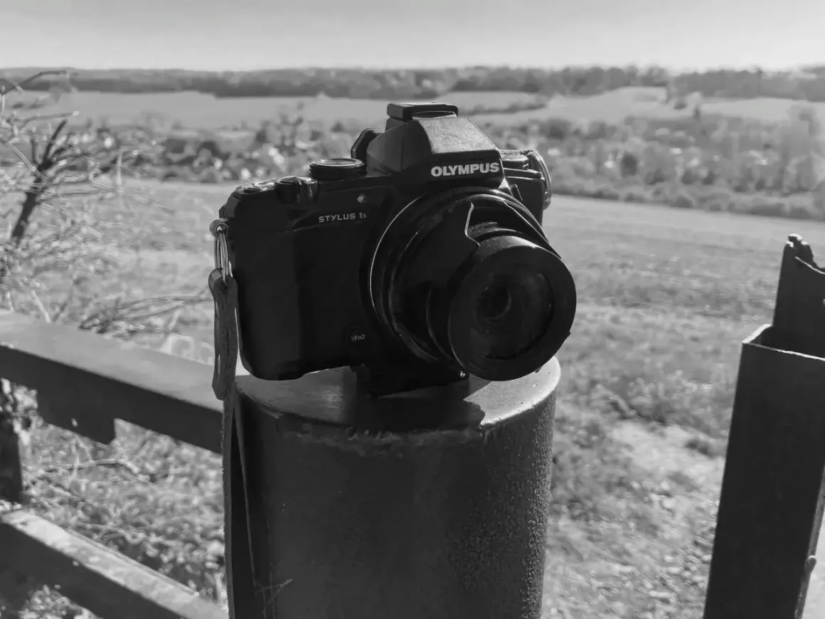 Olympus Stylus 1 camera staat op een paal, klaar om het landschap vast te leggen.