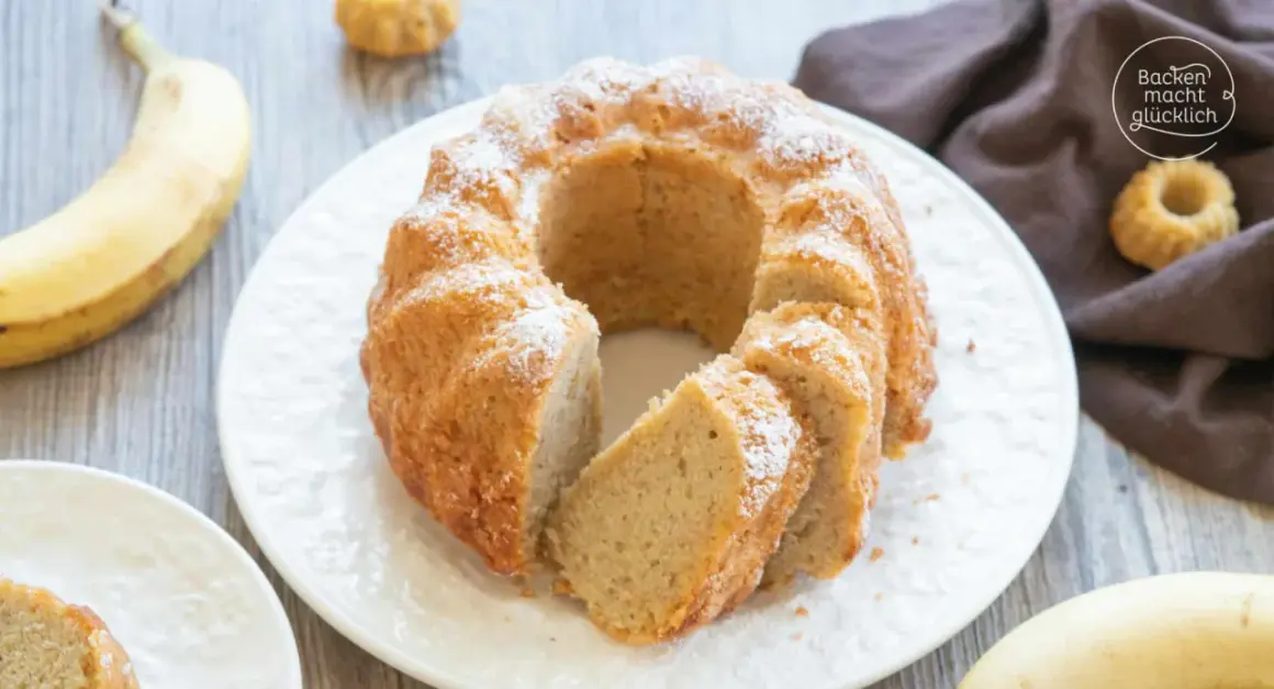 Reife Bananen verwerten: Ein saftiger Bananenkuchen mit Puderzucker bestäubt, daneben liegen frische Bananen.