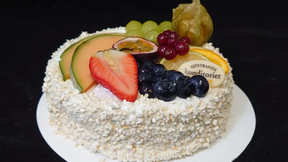 En vacker tårta, perfekt för att dekorera tårta med frukt. Toppad med melon, jordgubbar, blåbär, passionsfrukt och vindruvor.