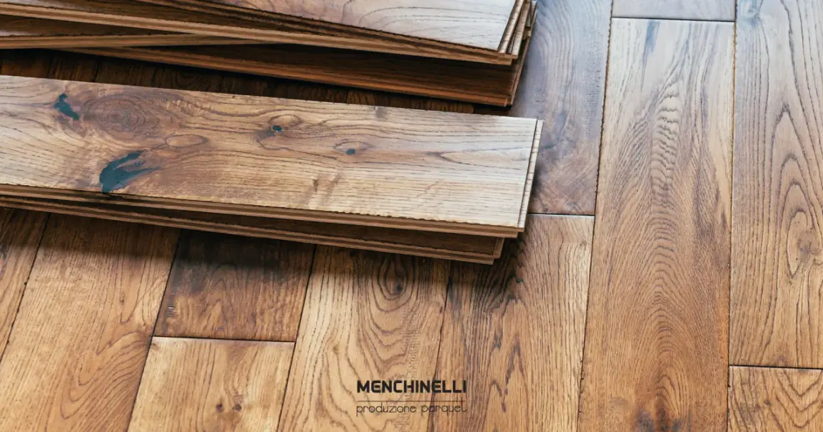 Pezzi di parquet in legno di rovere impilati, pronti per la finitura. La venatura naturale del legno è ben visibile.
