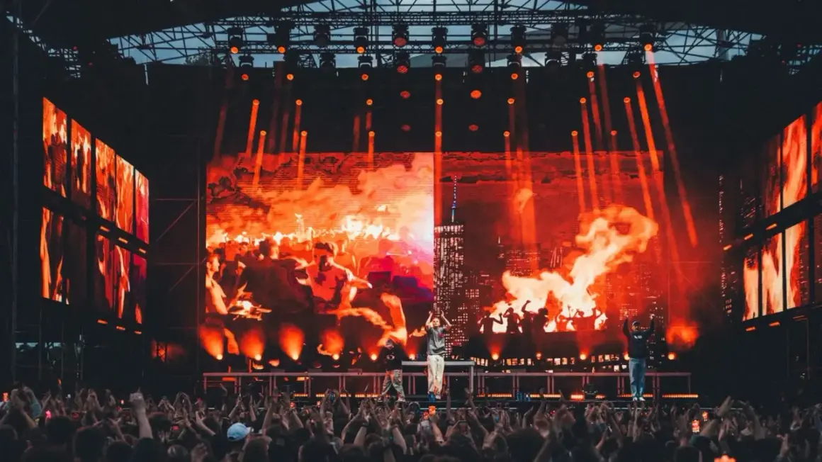 Koncert na festiwalu z ognistą scenografią i tłumem widzów.