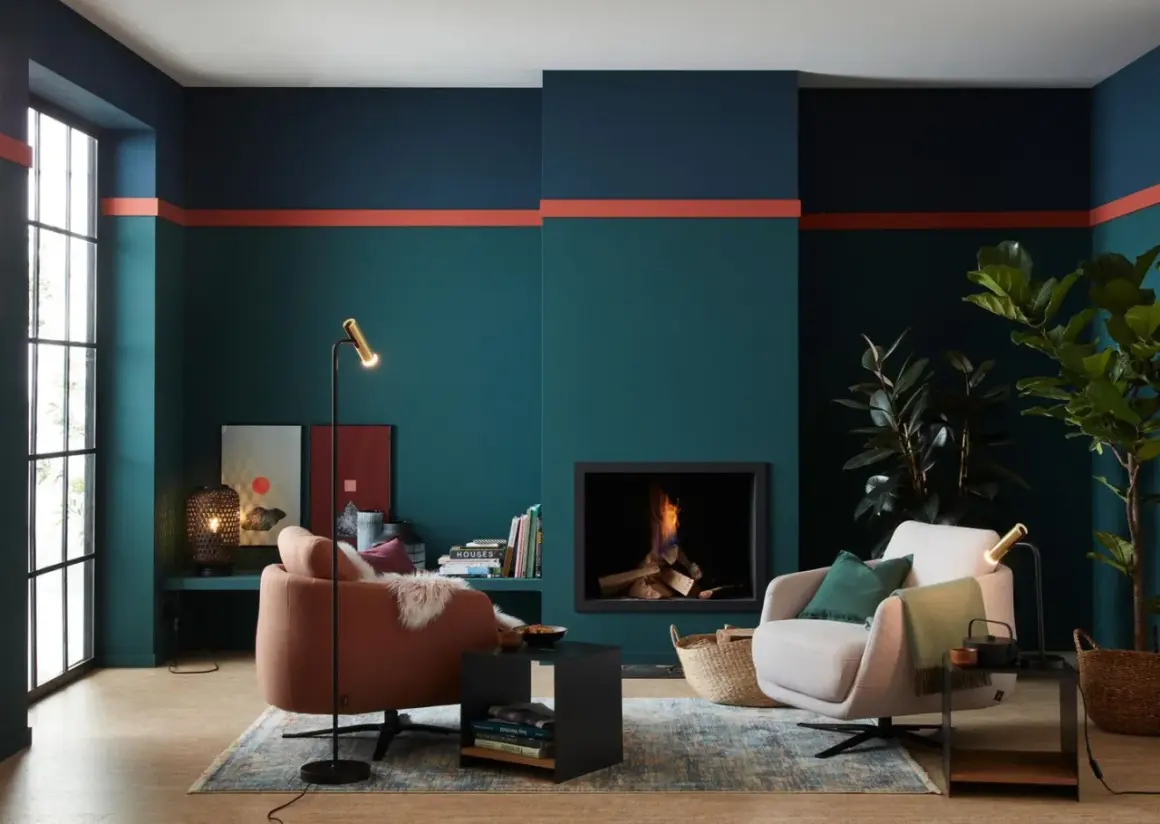 Moderne Wohnzimmer-farbgestaltung wand mit petrol, dunkelblau und korallenroten Akzenten. Gemütliche Sessel und Kamin sorgen für Wohlfühlatmosphäre.