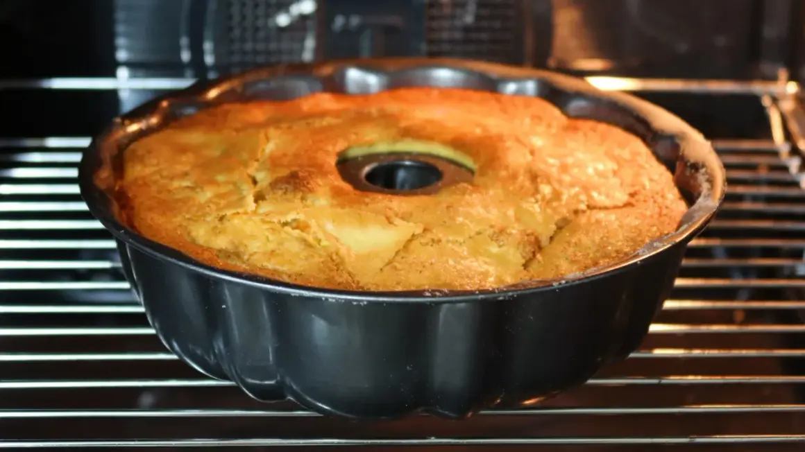 Bizcocho de manzana y naranja recién horneado en su molde, con un dorado perfecto. ¡Huele delicioso!