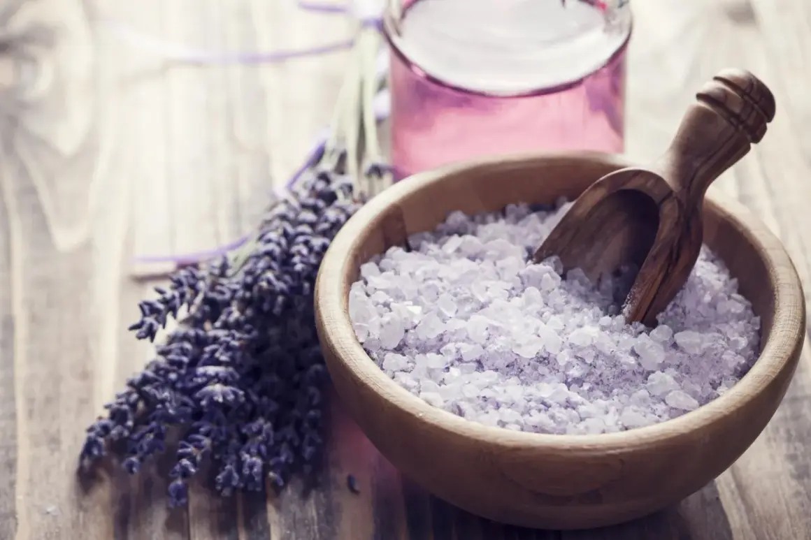 Lavendel badesalz selber machen: Eine Holzschale mit duftendem Lavendelsalz und ein Bündel frischer Lavendelblüten.