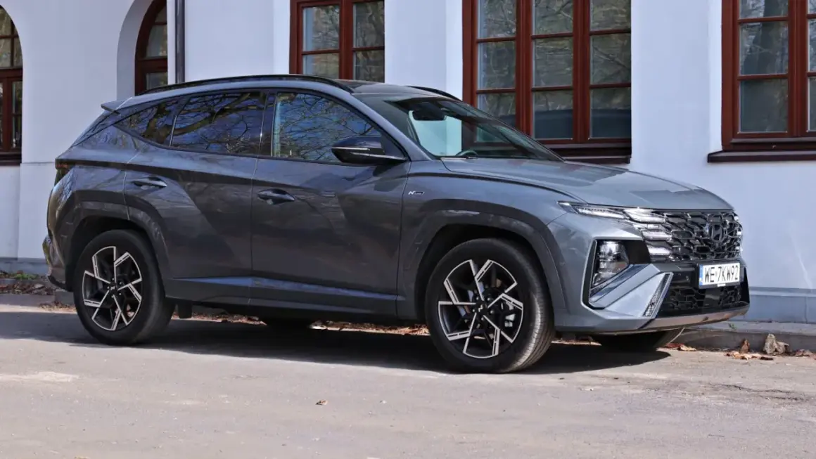 Szary Hyundai Tucson N Line zaparkowany przed budynkiem. Sprawdź aktualną hyundai tucson cena i ofertę.