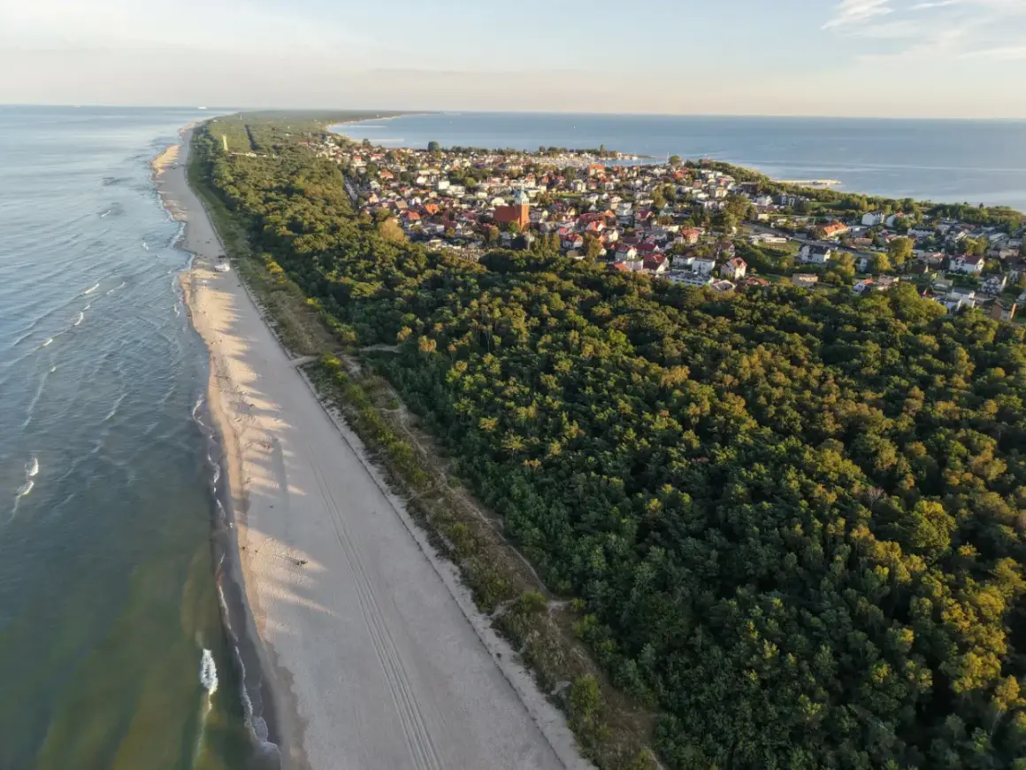 Plaża i las na Pomorzu, ukryte perełki, które warto odkryć. Widok z lotu ptaka na wybrzeże i urokliwe miasteczko.