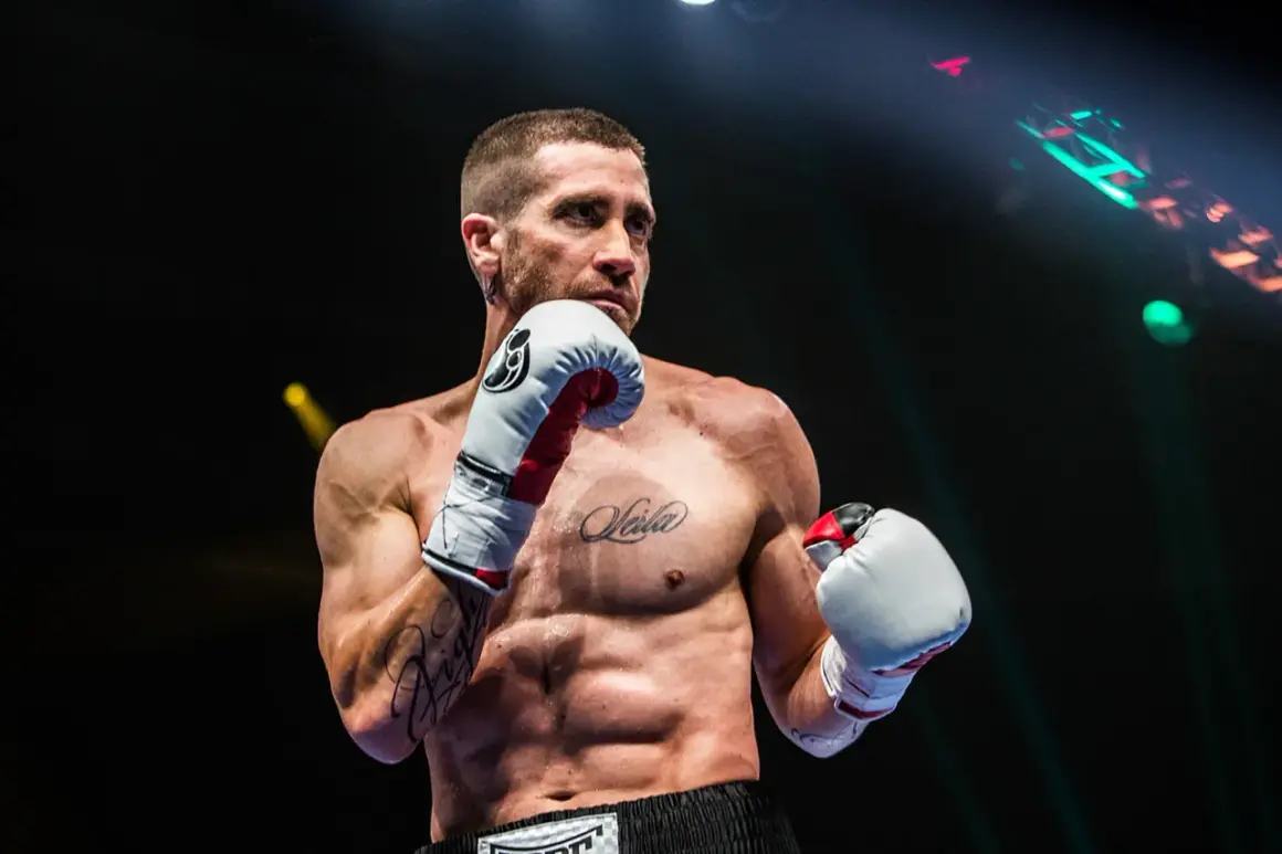 A boxer, possibly Jake Gyllenhaal, in an orthodox stance, ready to fight. His intense gaze suggests a southpaw opponent.