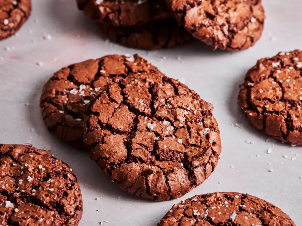 Knusprige brownie cookies mit Meersalzflocken, die auf einer hellen Oberfläche liegen.