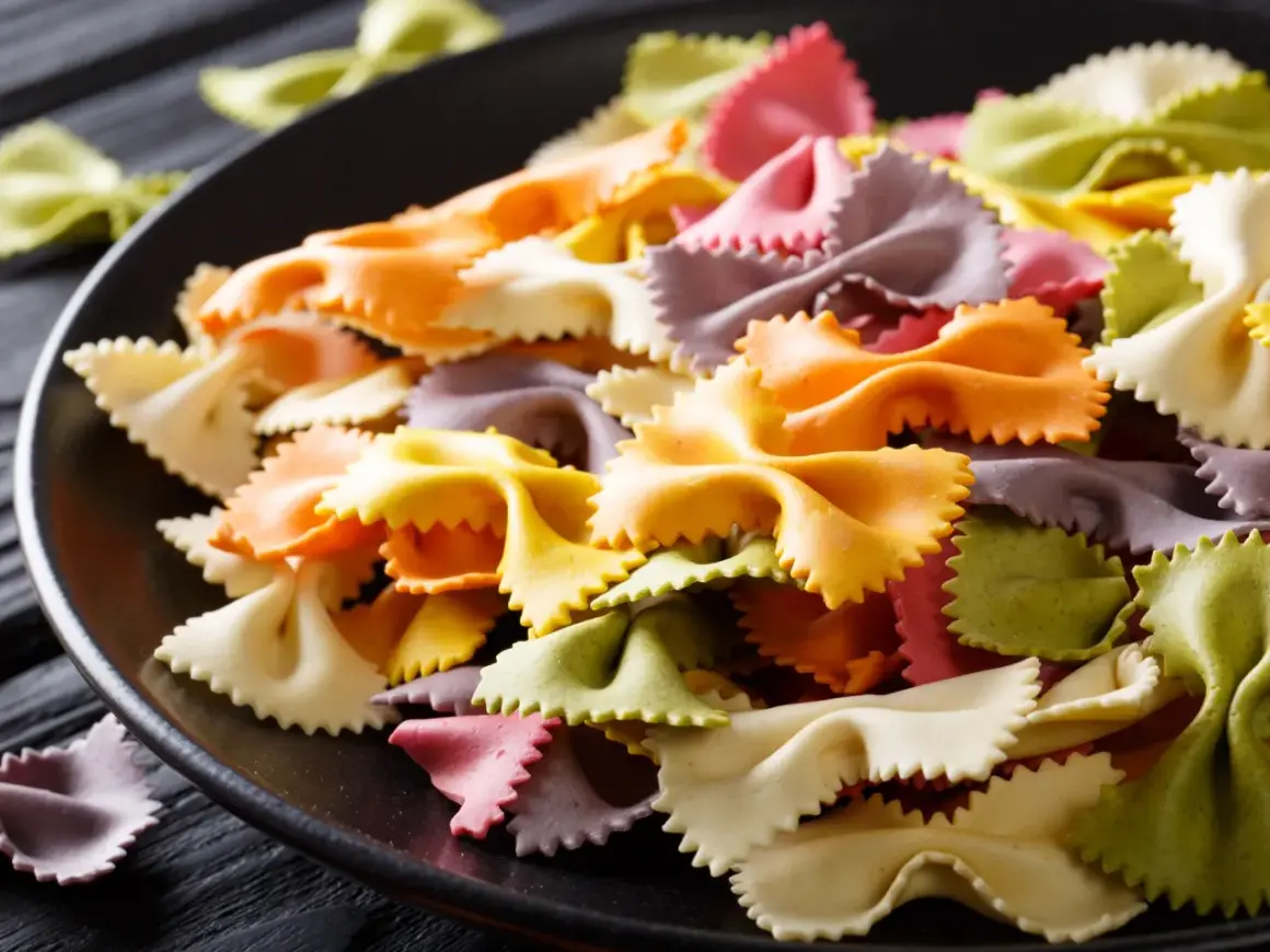 Bunte Farfalle-Nudeln auf schwarzer Platte. Ideen für blaues Essen Rezepte, die Spaß machen und schmecken.
