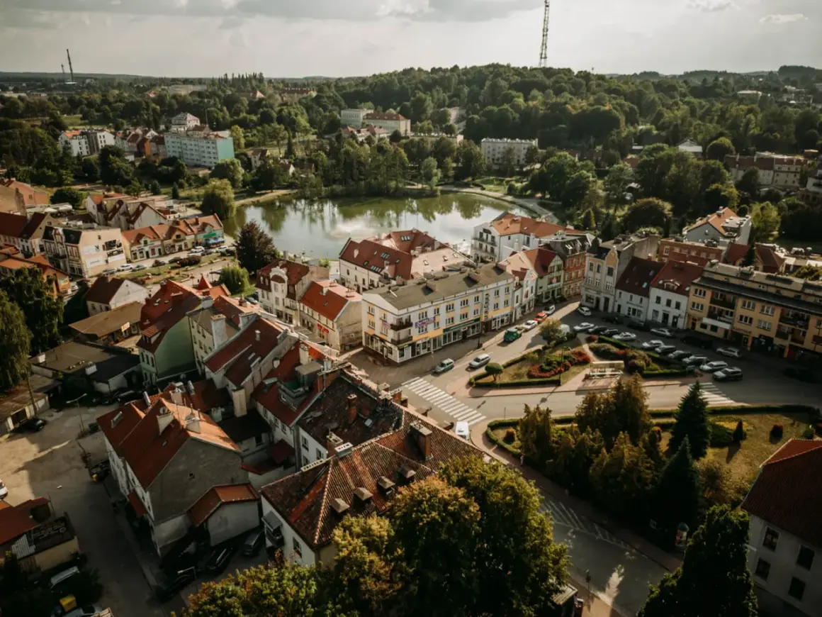Urokliwe Mrągowo z lotu ptaka. Jezioro, kolorowe kamienice i zielone dachy tworzą malowniczy krajobraz. Odkryj mrągowo atrakcje!