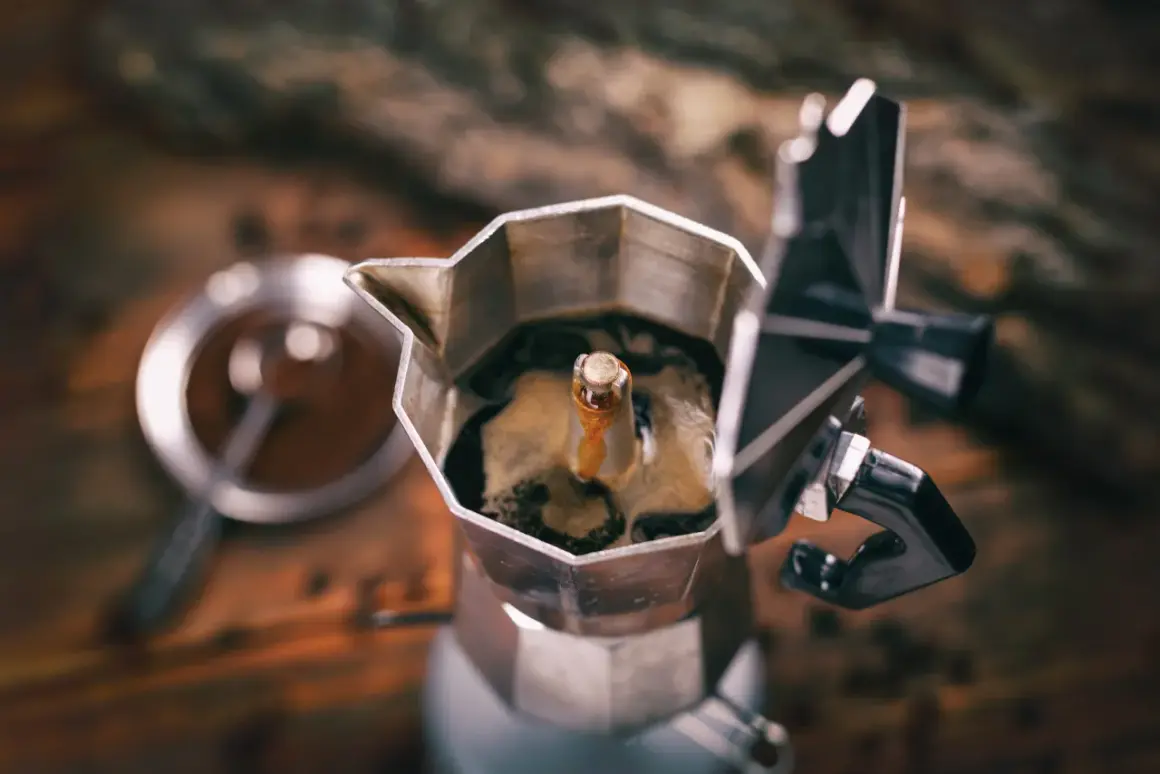 Caffettiera moka in primo piano, con il caffè che sale. Un rituale mattutino che, si dice, il caffè aiuta a digerire.