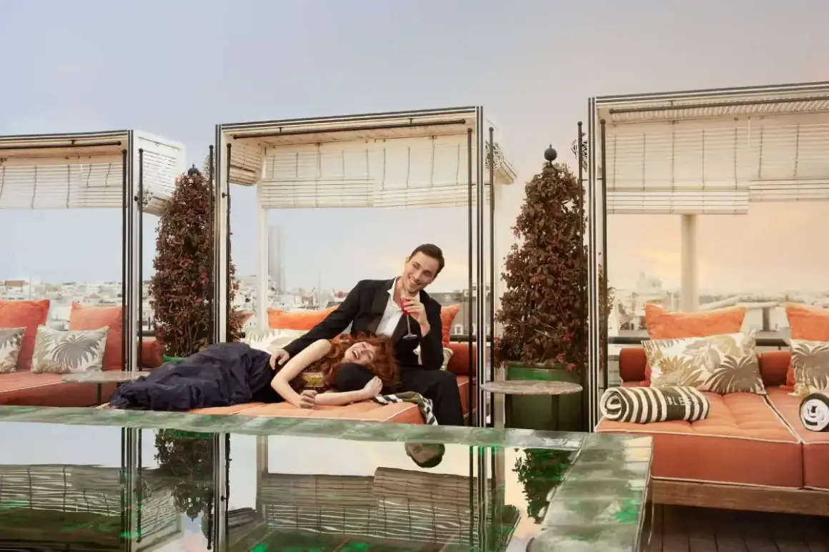 Coppia elegante su un rooftop a Madrid, godendosi cocktail e la vista. La **madrid vita notturna** è vibrante, e questo è il posto perfetto per viverla.