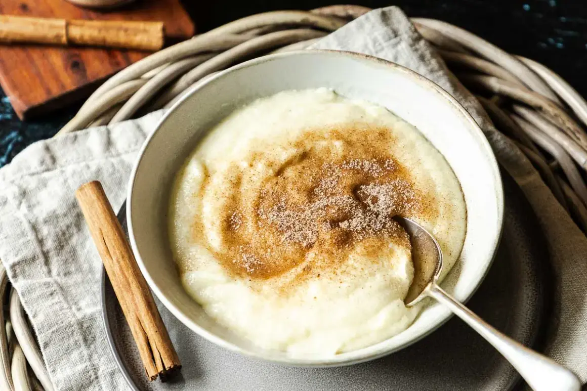 Cremiger Grießbrei mit Zimt und Zucker bestreut, ein einfaches und leckeres Grießbrei Rezept. Daneben liegen Zimtstangen.