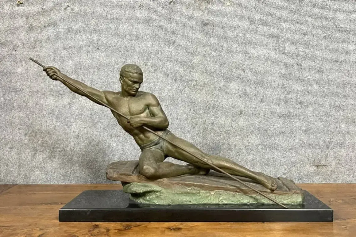 Sculpture d'un athlète en mouvement, tenant une lance. L'œuvre en bronze ou régule, est posée sur un socle en marbre noir.