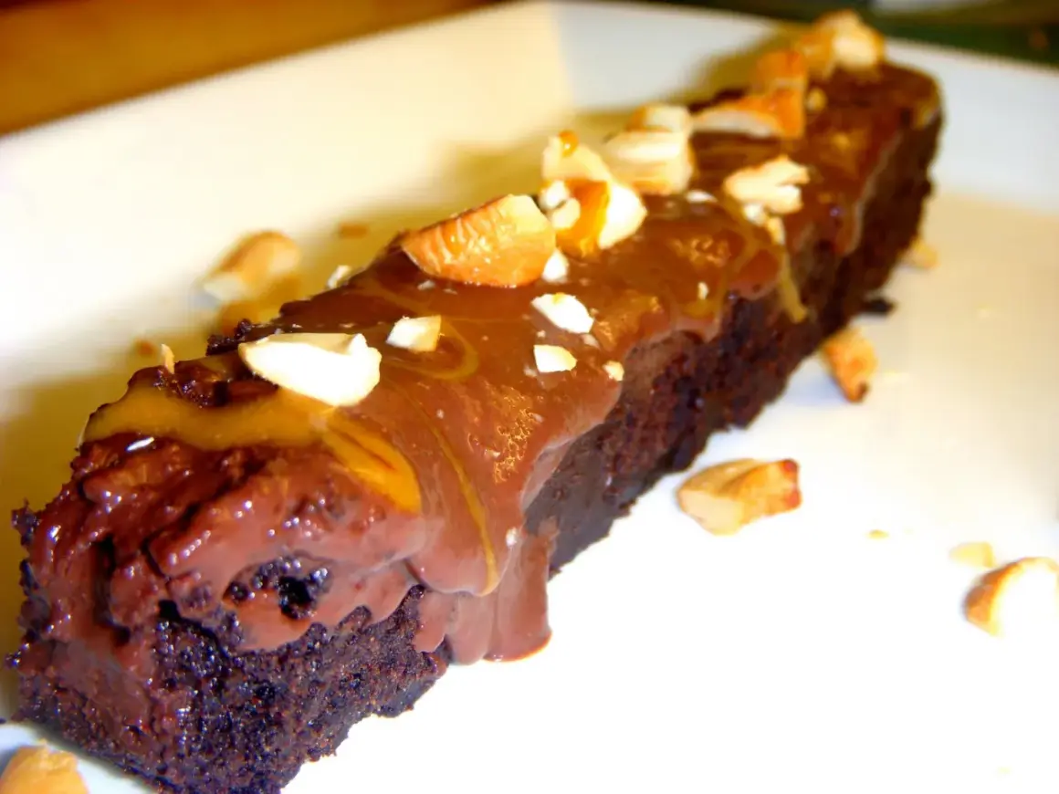 En bit fransk chokladtårta med chokladglasyr och nötter.