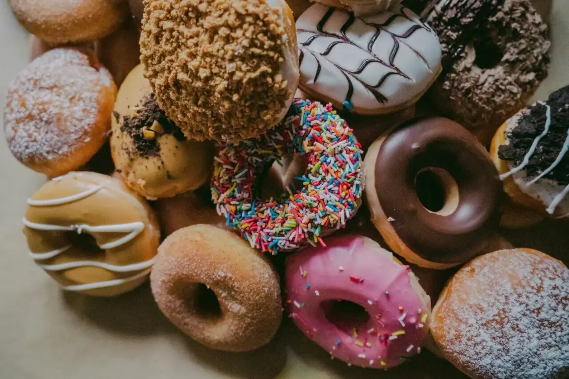 Kolorowe pączki, każdy z nich to mała bomba kaloryczna. Cukier, lukier, posypki – ile kalorii kryje się w tej słodkiej przyjemności?
