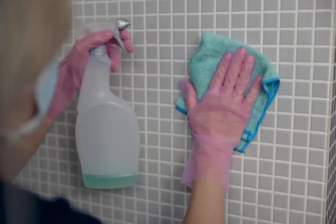 Ręce w różowych rękawiczkach czyszczą płytki. Zastanawiasz się, czym umyć fugi? Spray i ściereczka to dobry początek.