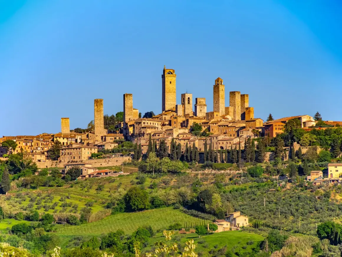 San Gimignano z wieżami, otoczone zielonymi wzgórzami Toskanii, gdzie dojrzewają winogrona na wino Vernaccia di San Gimignano.