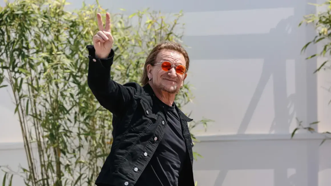 Bono con occhiali arancioni fa il segno di vittoria, forse un anticipo del nuovo u2 new album.