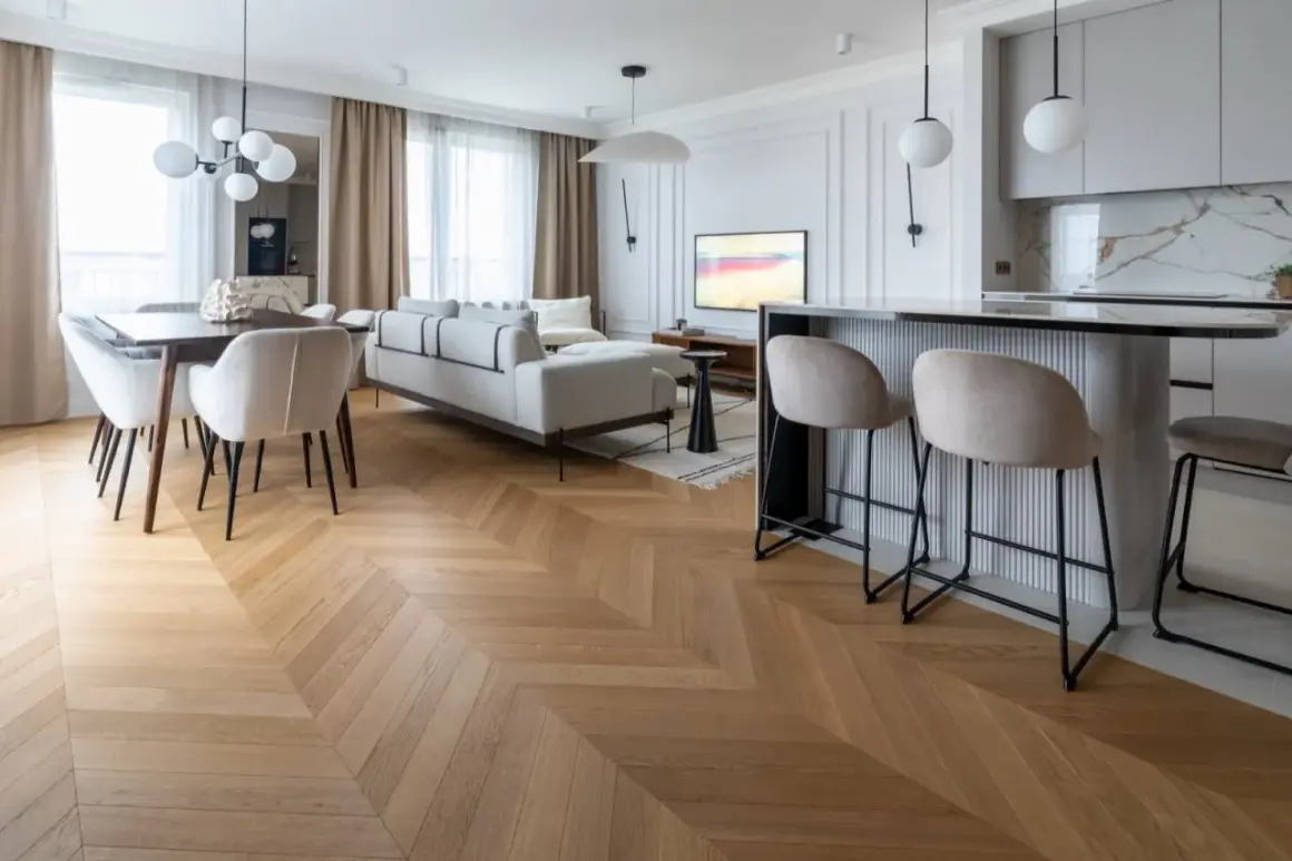 Elegancka jodełka z paneli winylowych, której grubość podkreśla jakość. Salon z sofą, jadalnia i barek kuchenny.