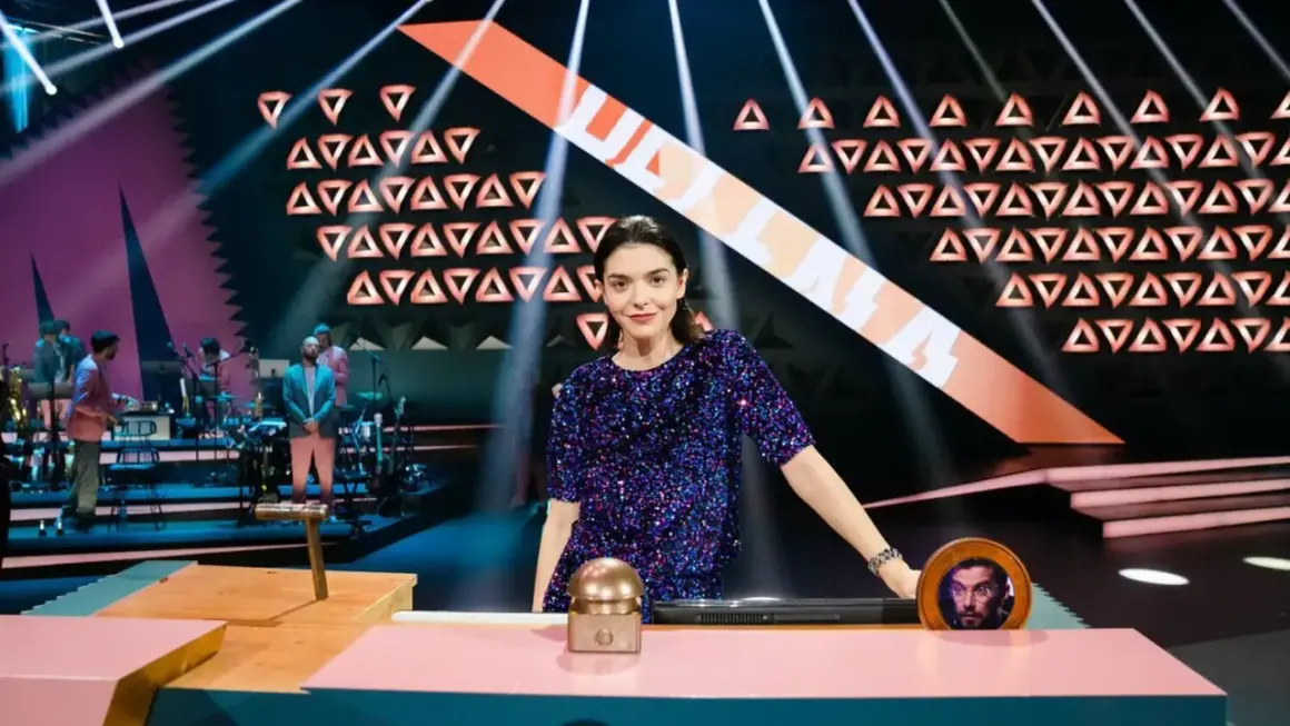 Eine Frau in Glitzerkleid steht im Rampenlicht, während eine Band im Hintergrund spielt. Wer stiehlt mir die Show?