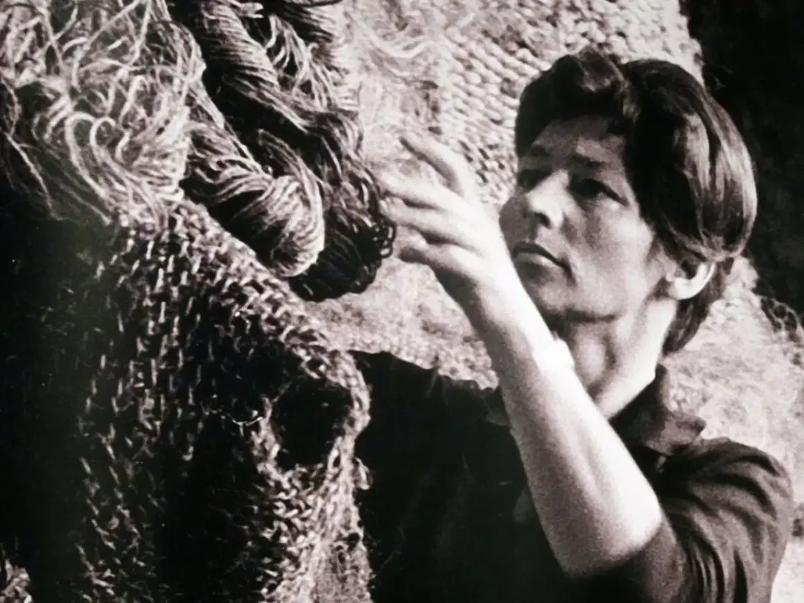 Magdalena Abakanowicz dotyka swojej monumentalnej rzeźby z włókien, tworząc dzieło sztuki.