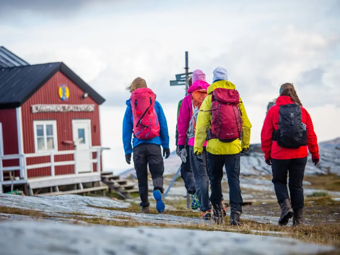 Vandringsgrupp närmar sig STF Sylarnas fjällstation. Vackert höstlandskap med molnig himmel.