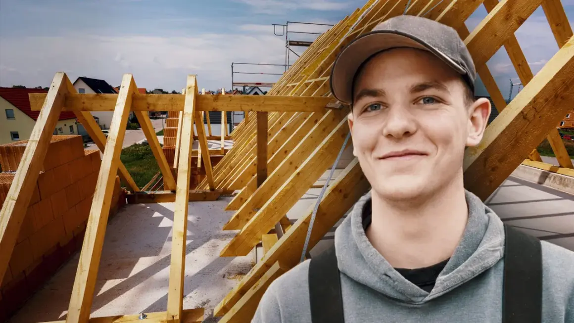 Junger Mann im Kapuzenpullover vor Dachstuhl. Informiert sich über zimmerer ausbildung gehalt netto.