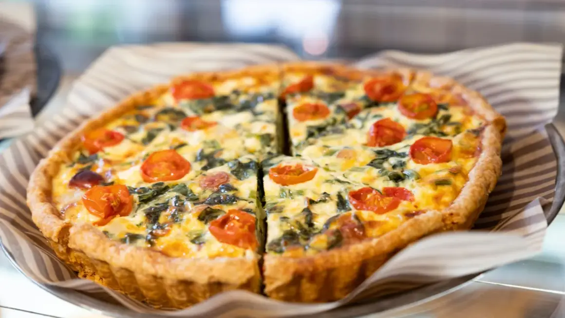 Torta salata con pomodorini e spinaci, perfetta per il tempo di cottura torta salata forno ventilato. Dorata e invitante.