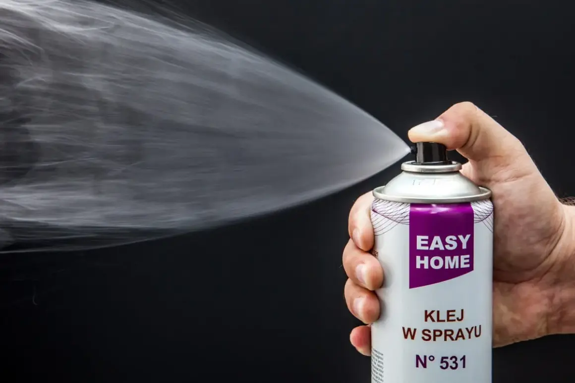 Dłoń trzyma puszkę z napisem "EASY HOME KLEJ W SPRAYU", rozpylając białą mgiełkę. Idealny do podsufitki.