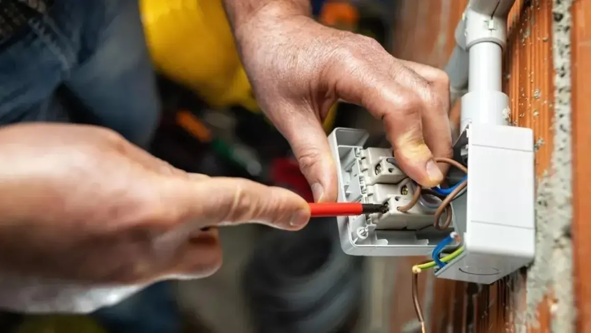 Elettricista collega cavi a una presa, mostrando le differenze tra i tipi di connessione.