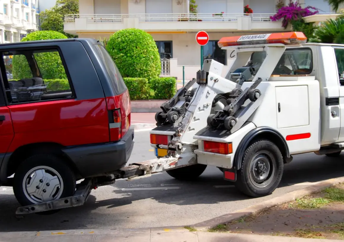 Une dépanneuse enlève une voiture rouge. Une amende pour stationnement illégal a peut-être été émise.