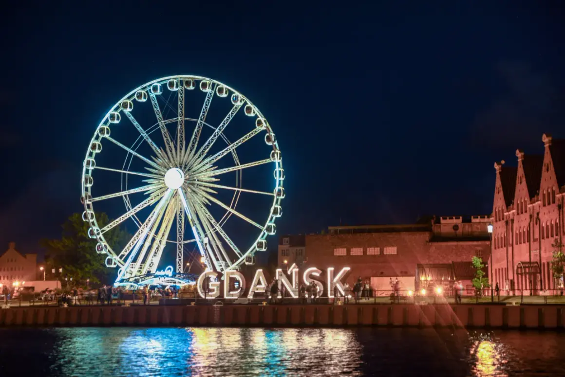 Nocne Gdańsk: diabelski młyn i wielki napis "GDAŃSK" to atrakcje dla dorosłych. Woda odbija światła miasta.