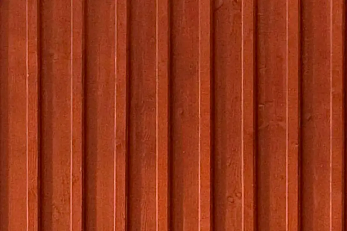 En närbild av en rödbrun, gammaldags lockpanel. Träets ådring syns svagt under färgen.