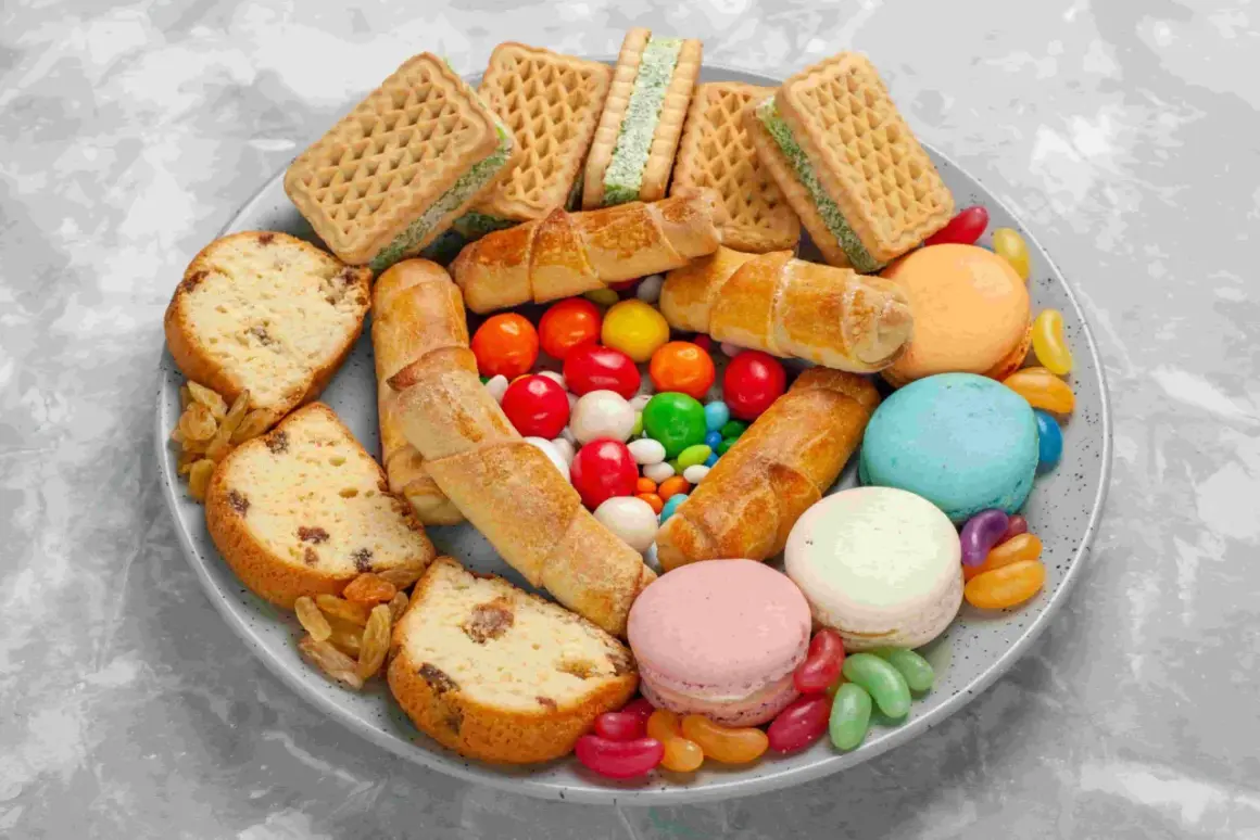 Talerz pełen słodyczy: ciasta, ciasteczka, makaroniki, cukierki żelki i draże.
