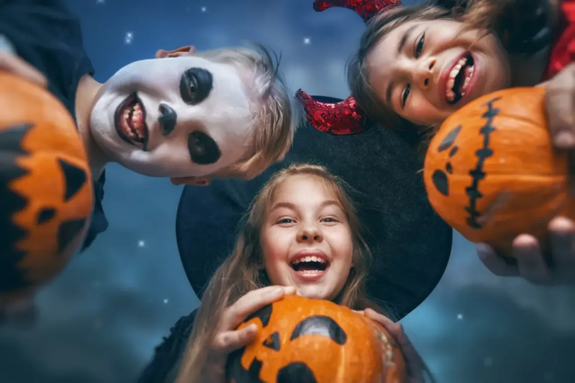 Barn med pumpor och utklädnader för ett rysligt halloween kalas.