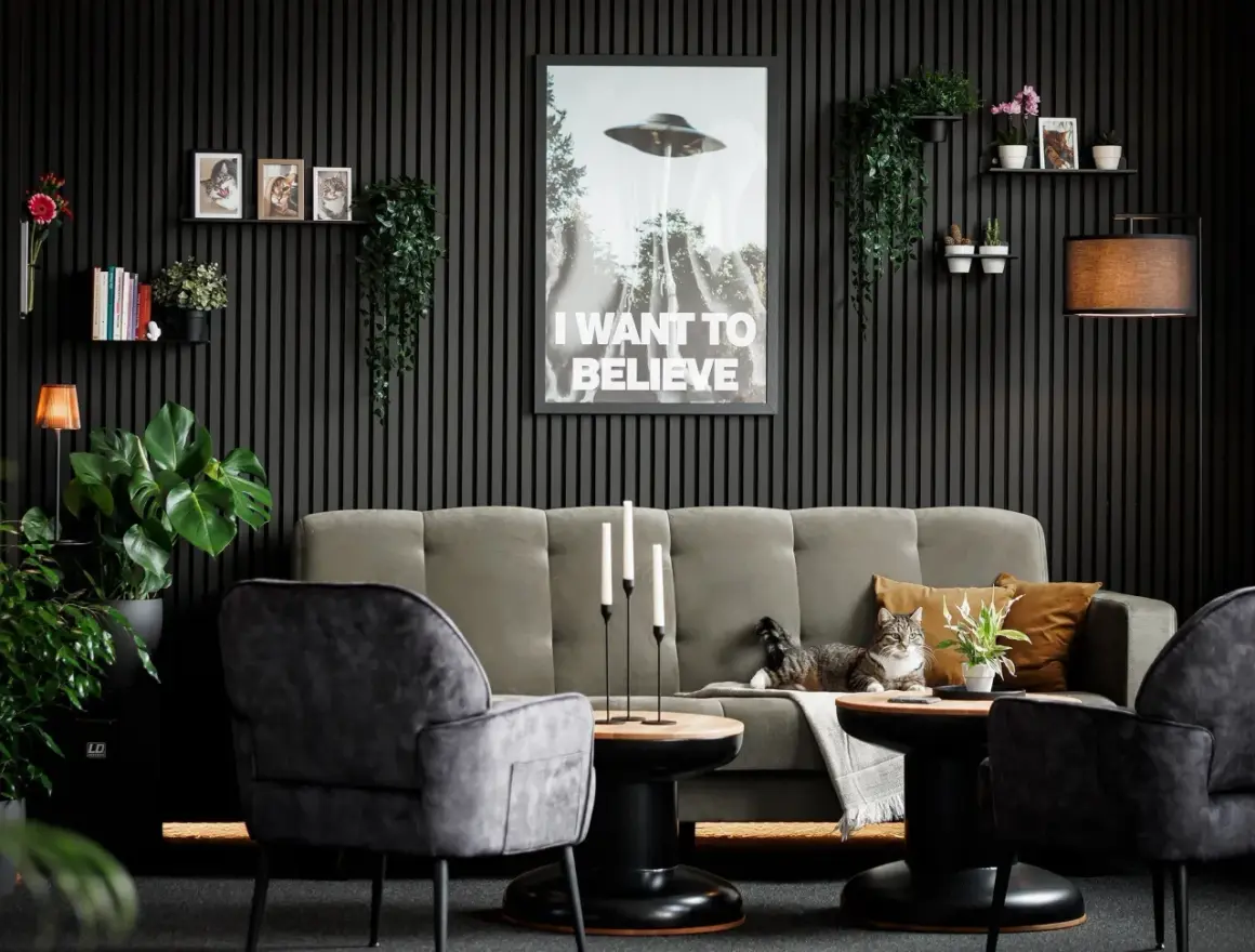 Gemütliches Wohnzimmer mit Akustikpaneelen an der Wand, einem Sofa, Sesseln, Pflanzen und einem Poster. Tolle Akustikpaneele Deko Ideen für ein stilvolles Zuhause.