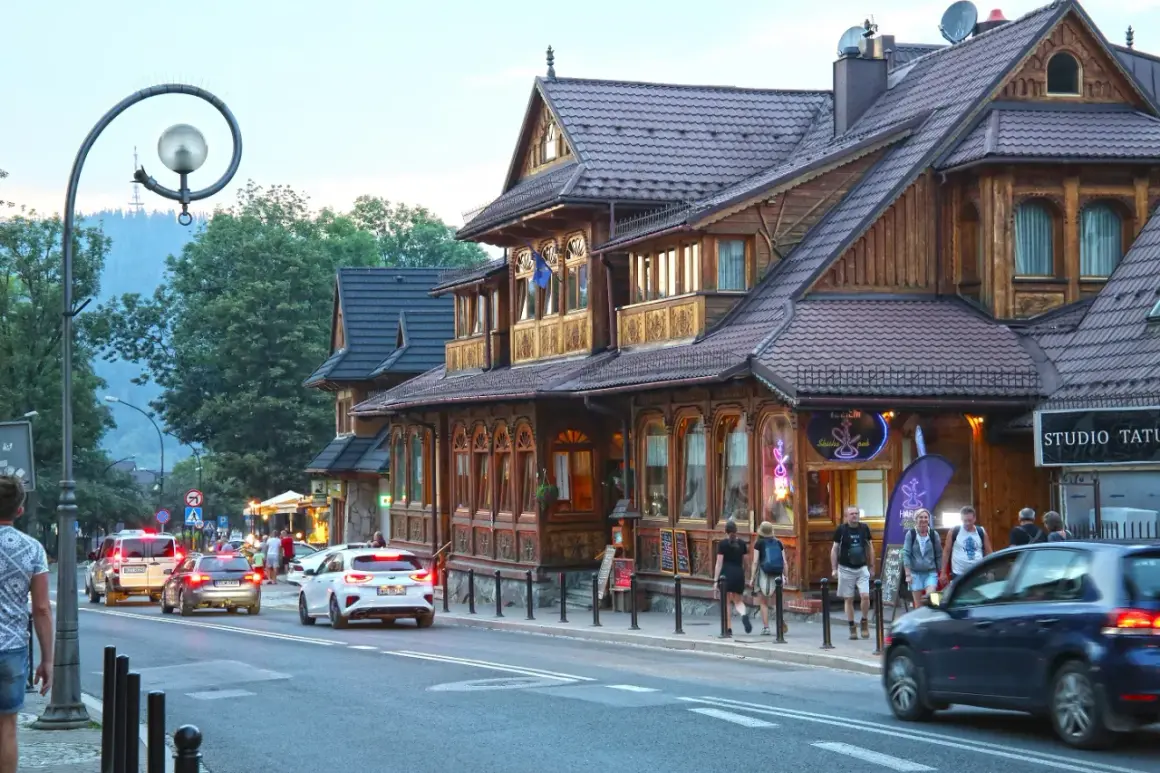 Spacer po tętniącym życiem białka tatrzańska centrum. Drewniane budynki, ruch uliczny i ludzie tworzą malowniczy widok.