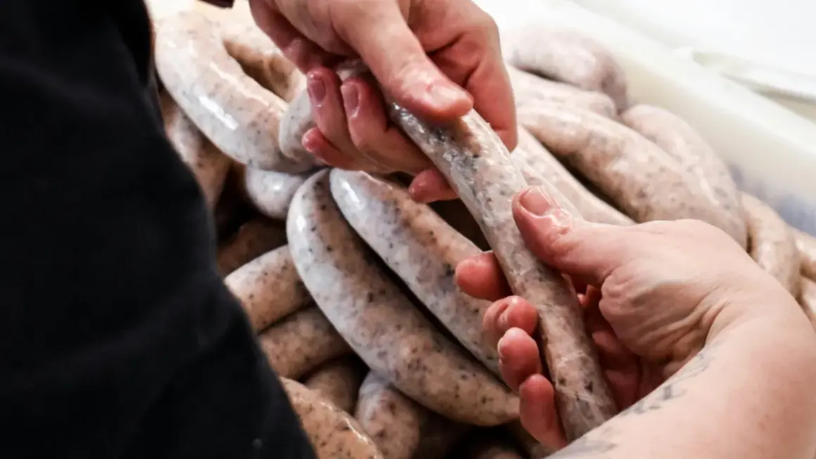 Dłonie formują białą kiełbasę, zastanawiając się, jakie przyprawy do białej kiełbasy nadadzą jej najlepszy smak.