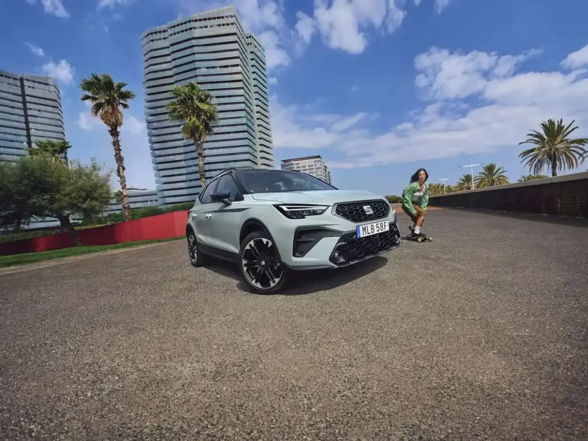 En Seat Arona står parkerad vid en strandpromenad med en person på skateboard i bakgrunden. Inga problem med denna bil.