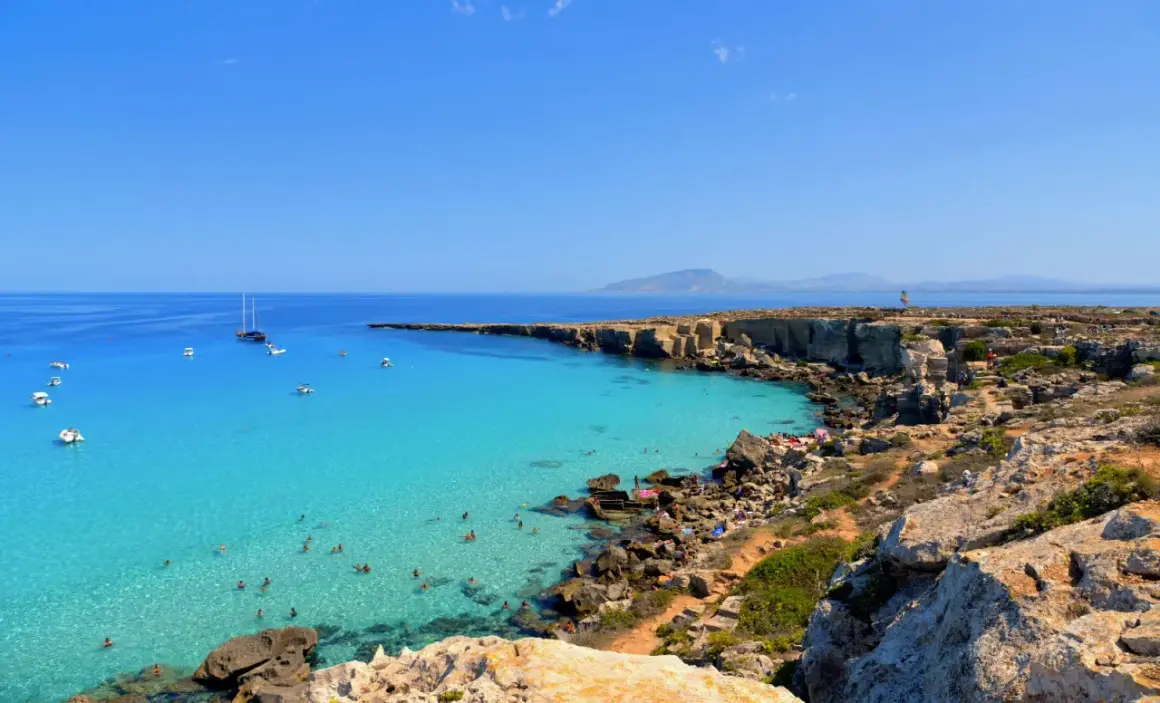 La spiaggia più bella di Favignana: acque cristalline, scogliere dorate e barche all'ancora. Un paradiso terrestre.