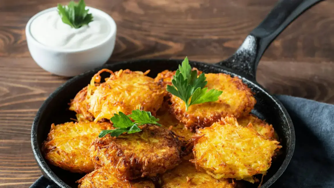 Goldbraune Kartoffelpuffer im Gusseisenpfännchen, perfekt für ein Kartoffelpuffer Rezept. Dazu ein Schälchen cremiger Dip.