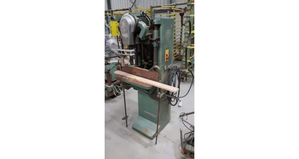 Machine à bois verte, une mortaiseuse à chaîne, avec une pièce de bois en position.