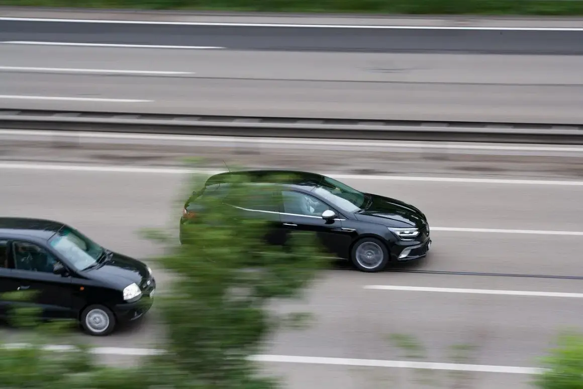Czarny samochód wyprzedza inny pojazd na autostradzie.