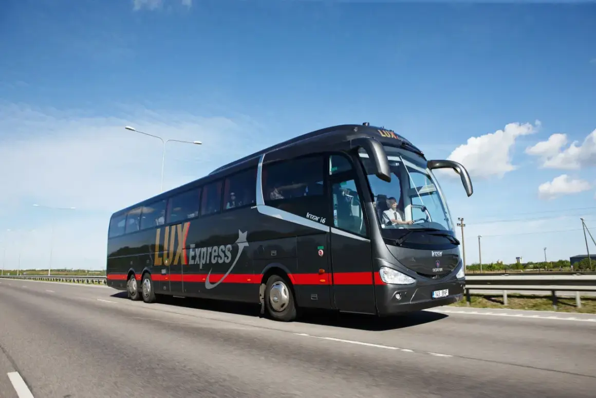Czarny autokar Lux Express z napisem "Podlasie Express Białystok-Warszawa Okęcie" jedzie po autostradzie.