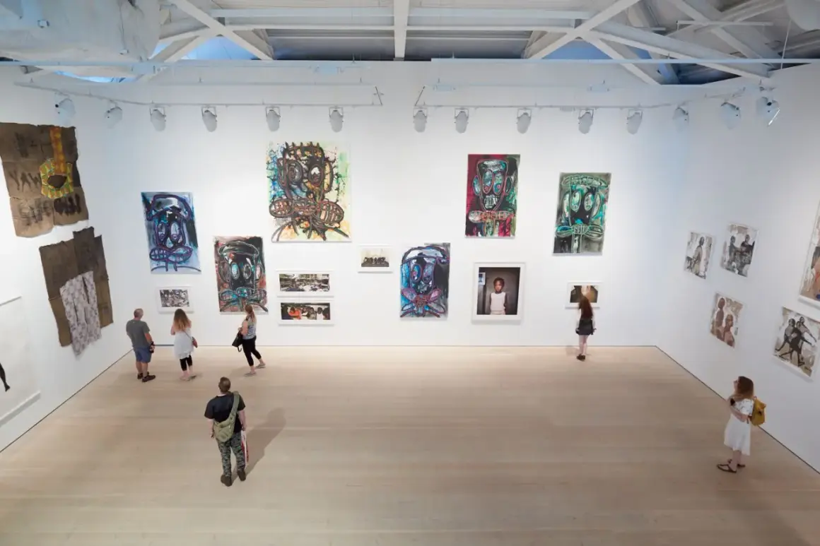 Visitors explore a vibrant exhibition, showcasing bold portraits and mixed media pieces that define the dynamic London art scene.