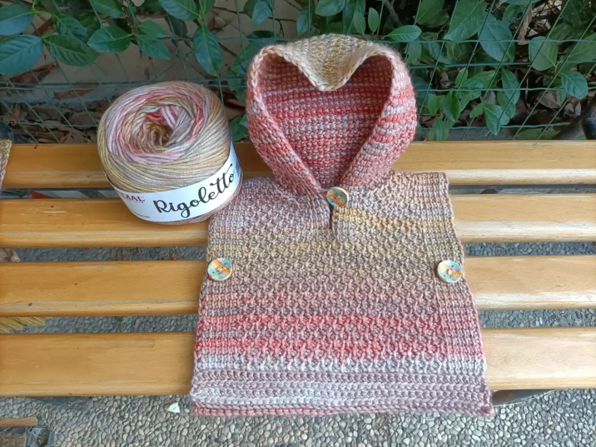 Uncinetto magico per un poncho colorato, con gomitolo Rigoletto e bottoni decorativi.